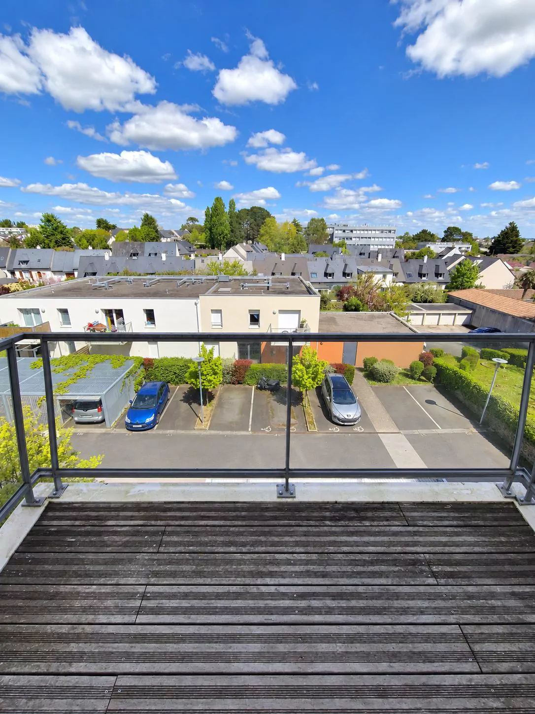 Vue depuis le balcon du troisième étage sur la cour arborée et les toits