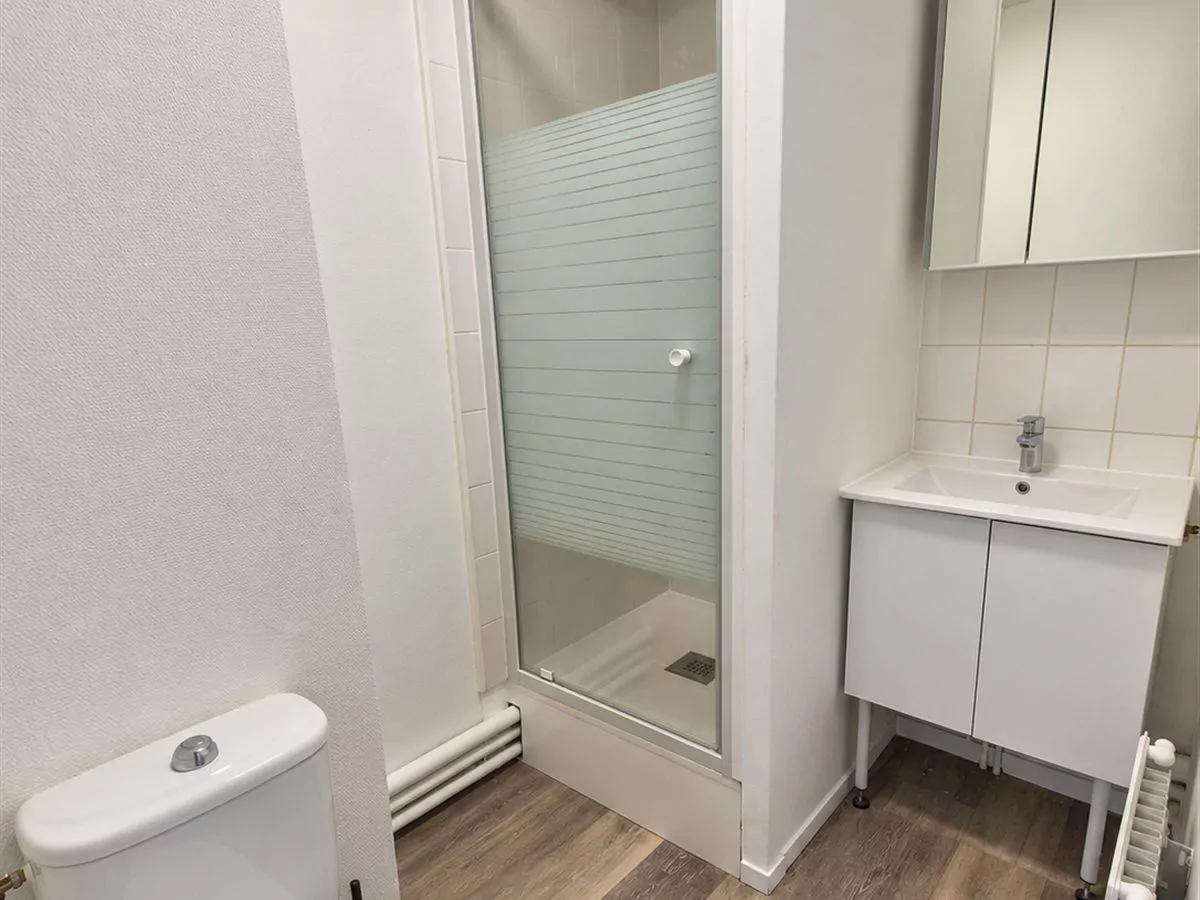 Salle d'eau après travaux : sol neuf, murs repeints, meuble vasque et armoire à glace